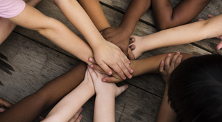 Diverse-hands-join-together-on-the-wooden-table-685866272_2046x1469.jpeg